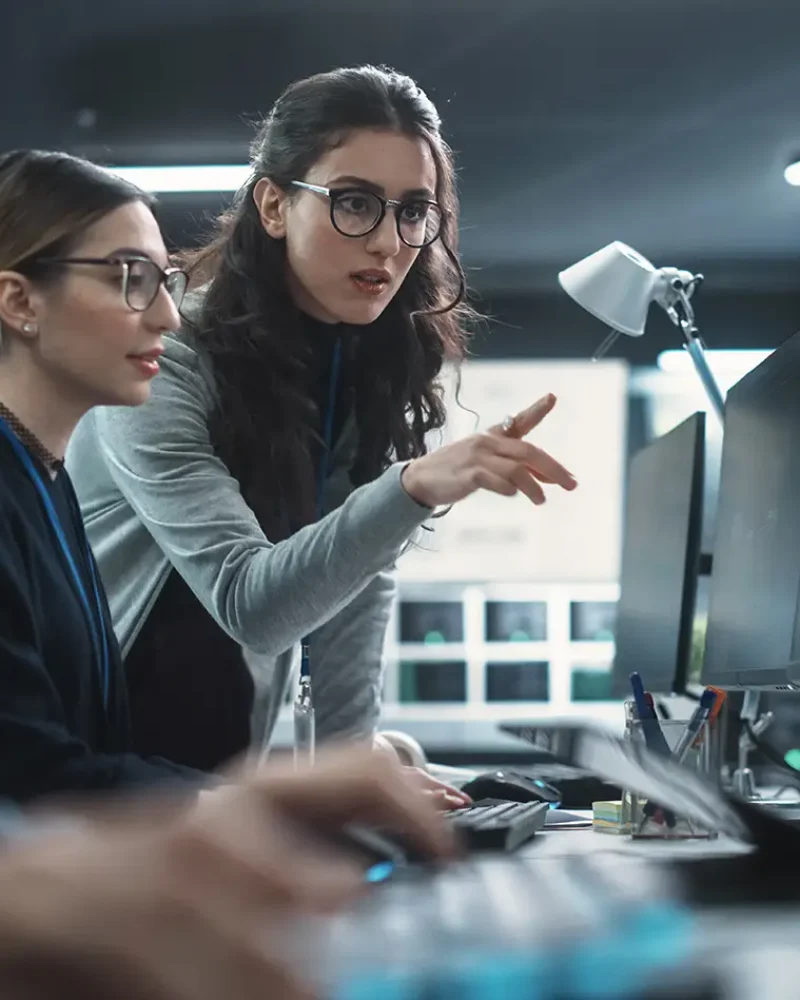 Two Beautiful Women Working in a Cyber Security Software Development Department. Young Manager Updating Software Developer on the Artificial Intelligence Safety Project