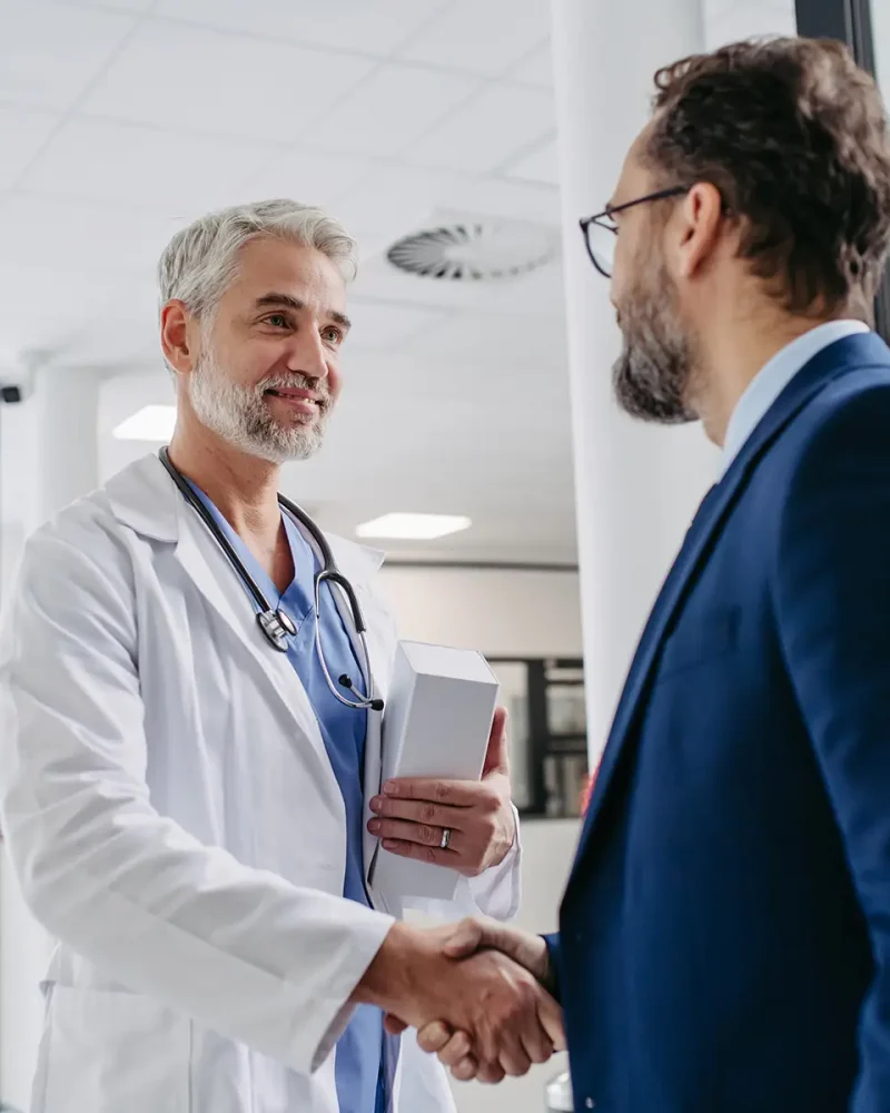 Pharmaceutical,Sales,Representative,Presenting,New,Medication,To,Doctor,In,Medical Pharmaceutical sales representative presenting new medication to doctor in medical building, shaking hands.